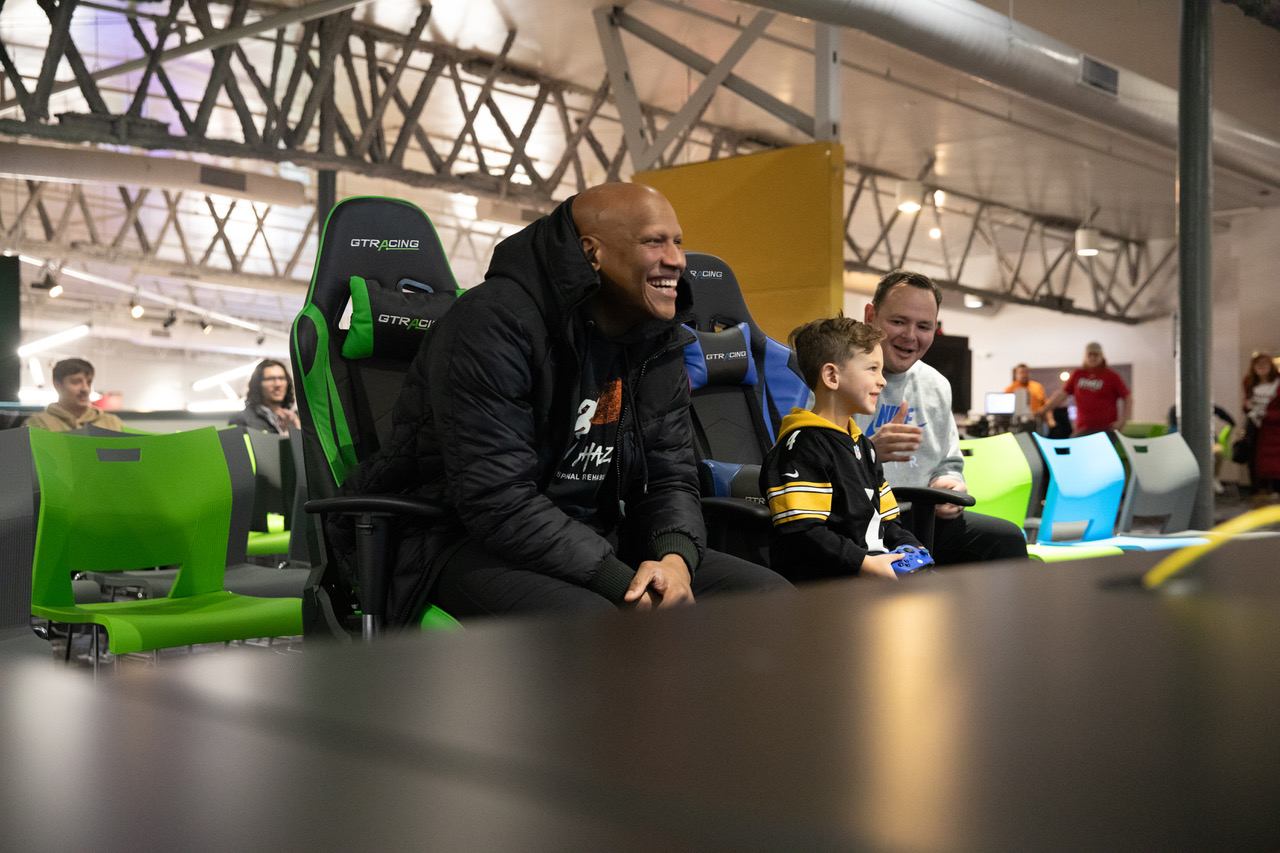 Ryan Shazier smiling beside a young participant holding a controller at a community Madden gaming event